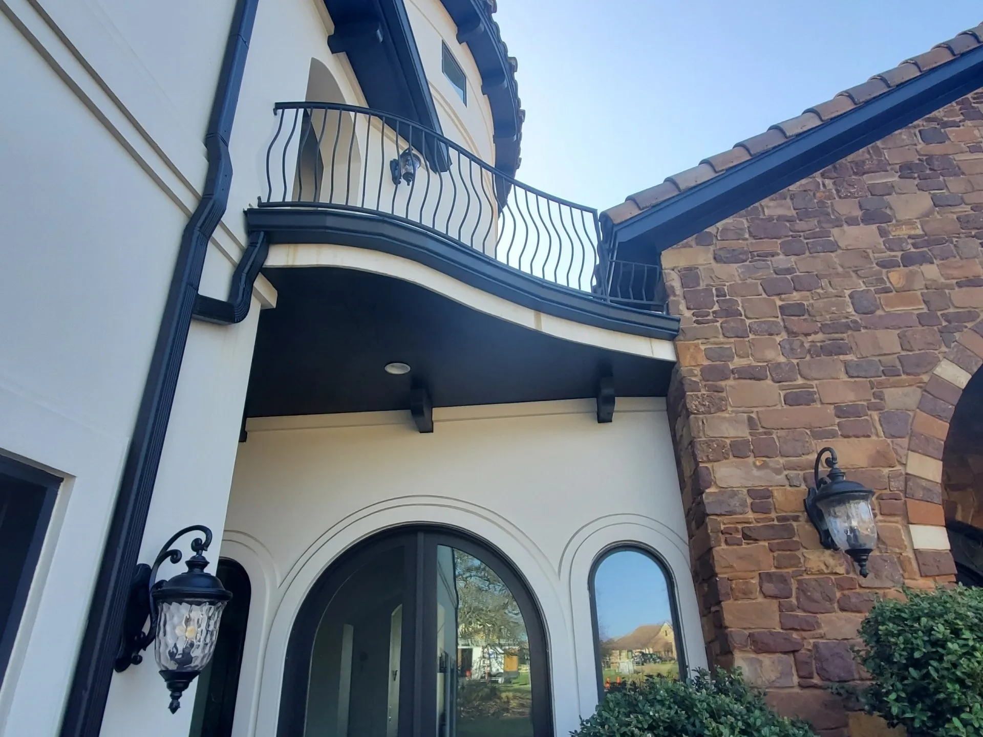 Dark seamless gutters and downspouts on a stucco and stone home in Austin
