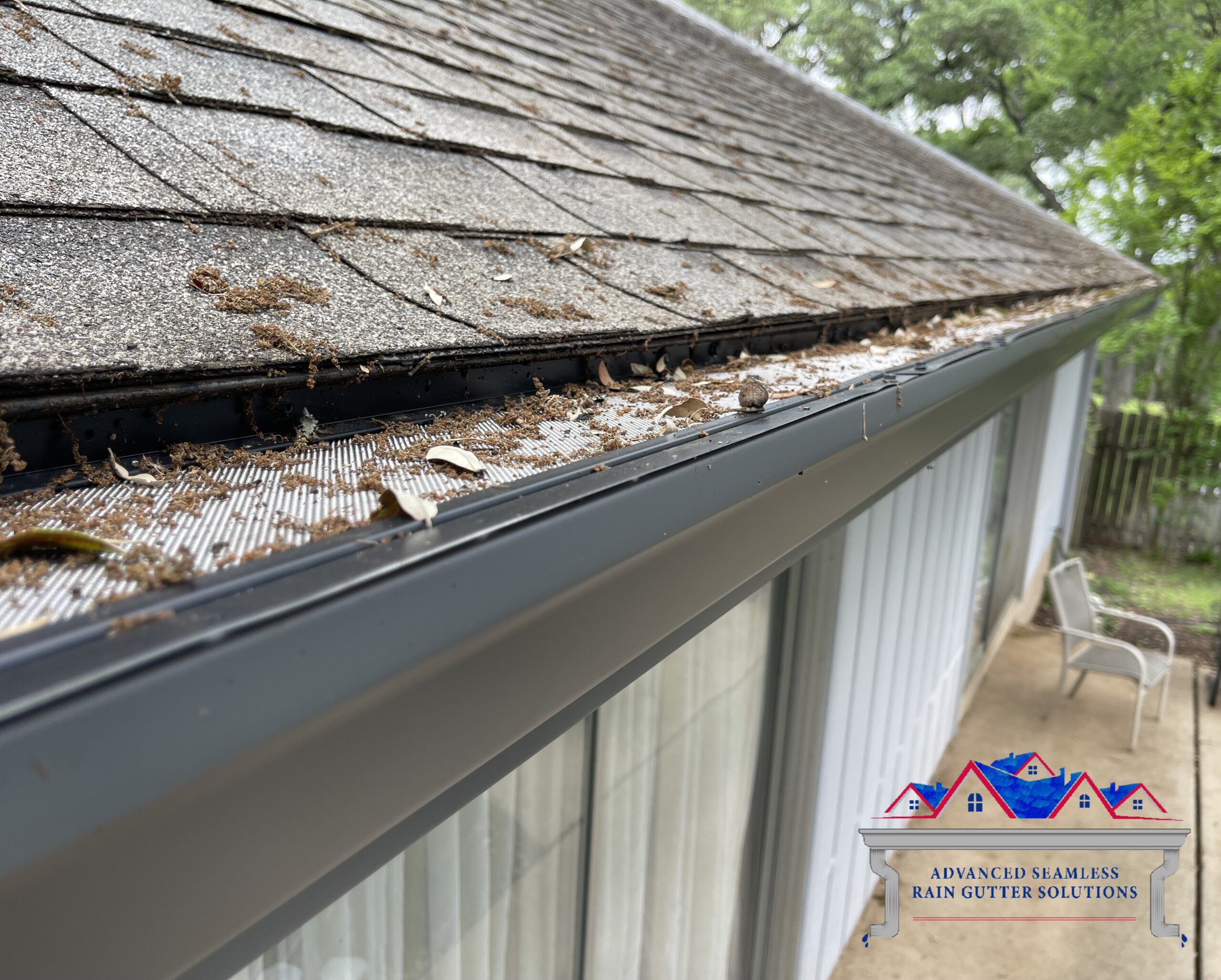 Fine mesh gutter guard on a dark seamless gutter holding back oak leaves and catkins