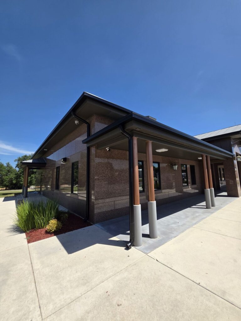 Oversized commercial gutter and downspouts along a covered walkway on a masonry office building