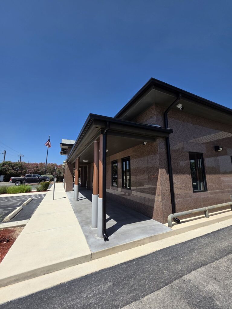 Commercial downspouts discharging along a covered entry walkway