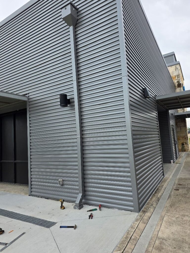 Custom rectangular downspout with a conductor head on a corrugated metal commercial building