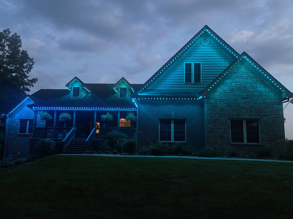 Permanent roofline lighting installed along the gables and eaves of a home at dusk
